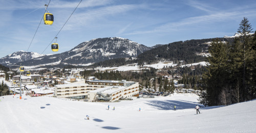 Skipiste mit Gondellift, im Hintergrund das Clubhotel Robinson Fieberbrunn